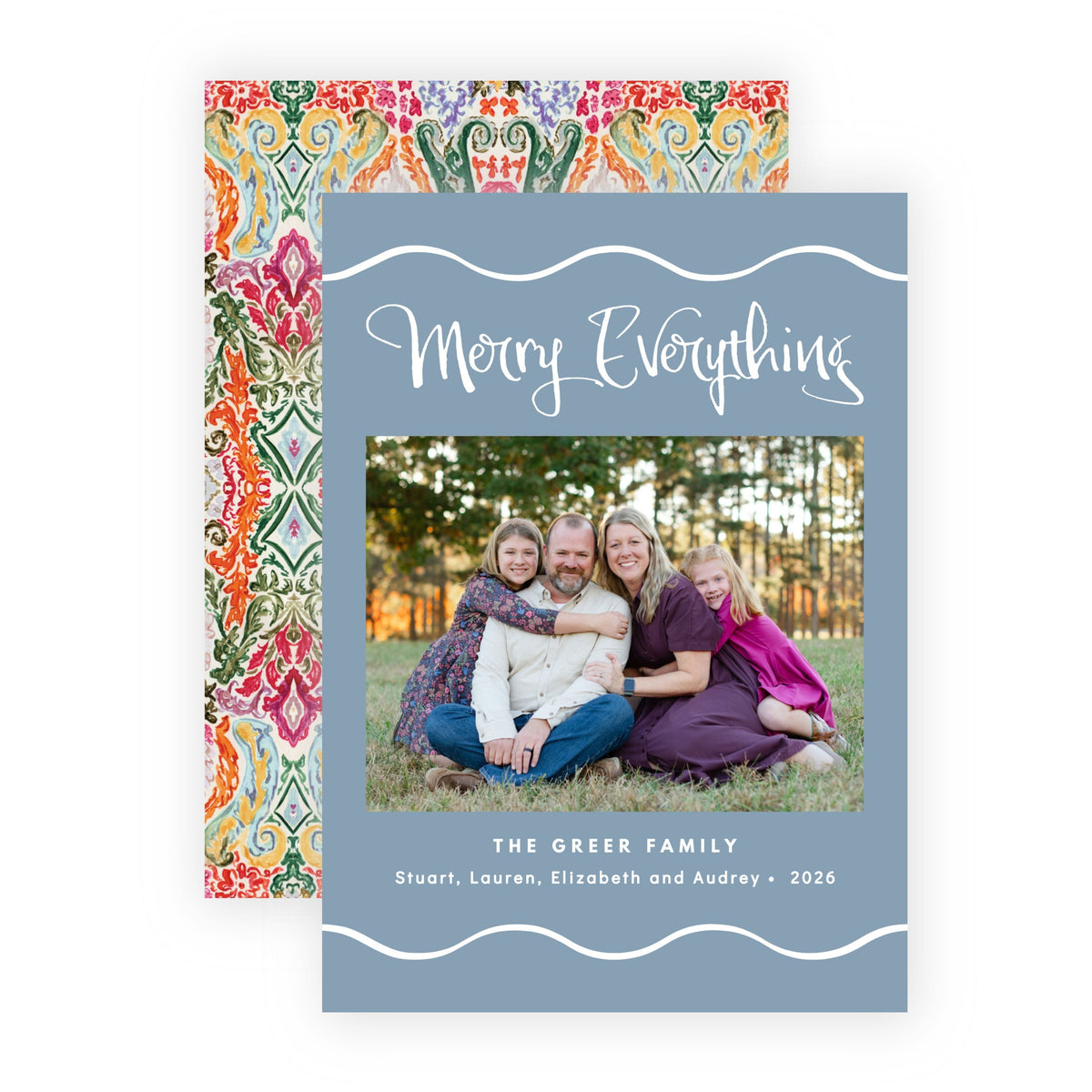 A personalized holiday greeting card with a slate blue front and a colorful patterned back, shown on a clean white background. The front features a photo of a family and the text 'Merry Everything' and 'The Green Family'.
