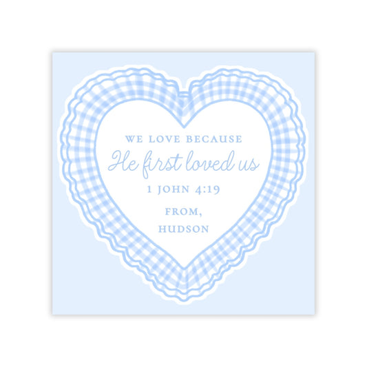 The image is a heart-shaped graphic with a blue and white checkered pattern around it. Inside the heart, there is text that reads "We love because He first loved us 1 John 4:19 FROM, HUDSON".