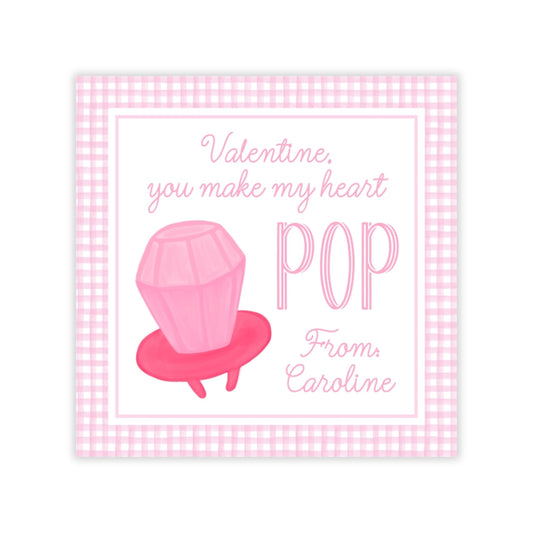 The image is a Valentine's Day card with a pink diamond-shaped object, likely a pop or lollipop, and a message that reads "Valentine, you make my heart POP From: Caroline".